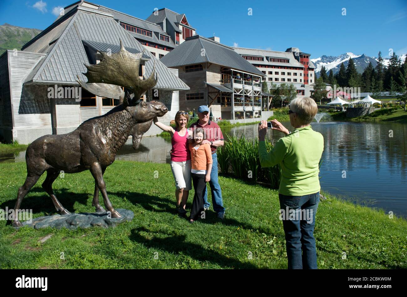 Grandparents photographing granddaughters with elk statue at Alyeska resort, Girdwood, Alaska, USA Stock Photo