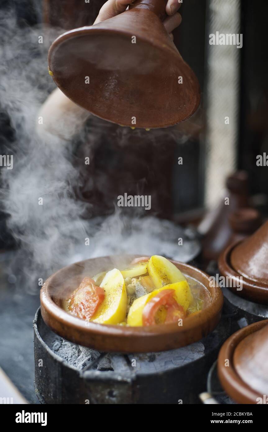 Hand lifting lid of tagine cooking in street, Casablanca, Morocco Stock Photo