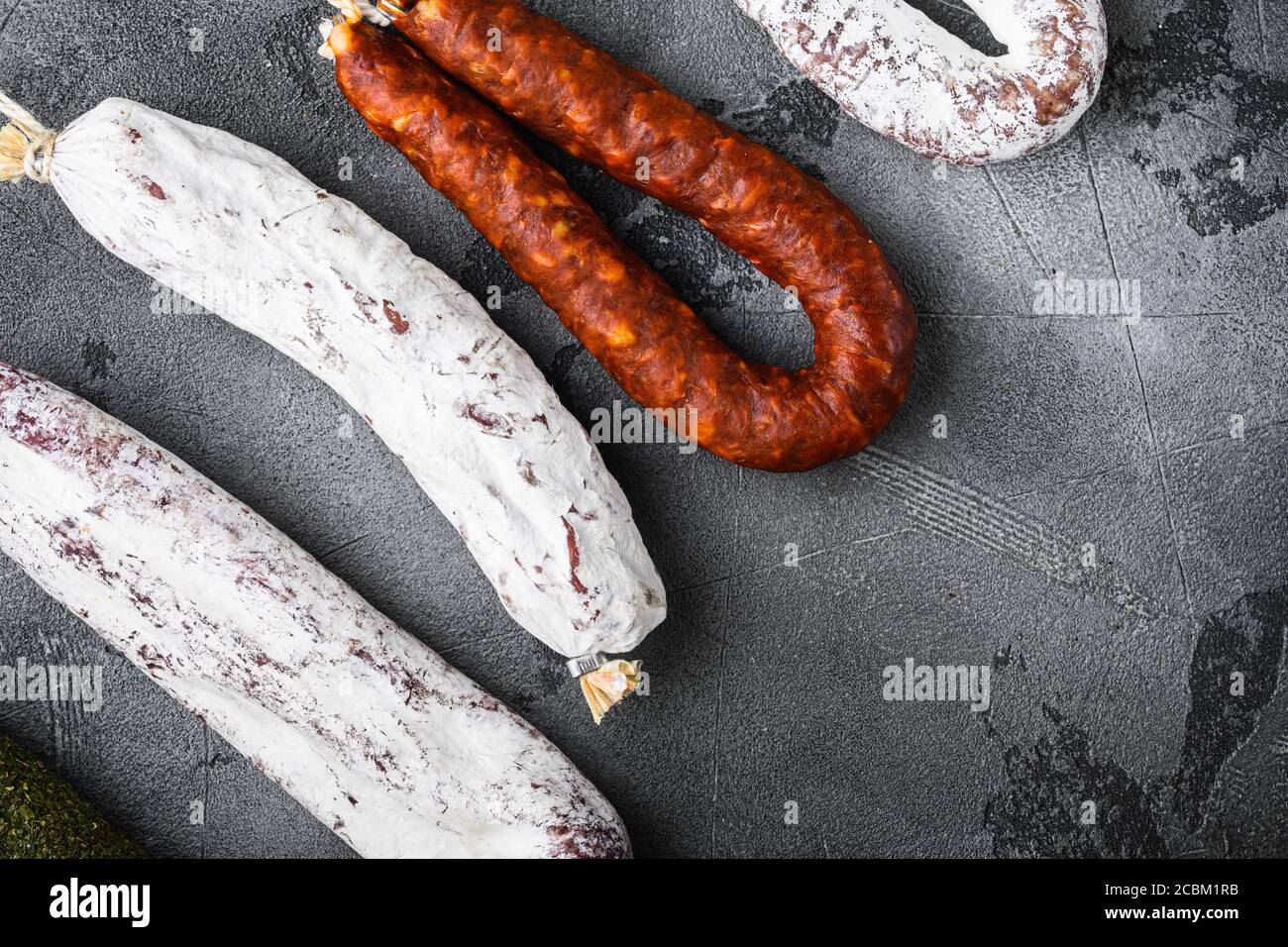 Spanish dry salami from a rack at market on grey textured background