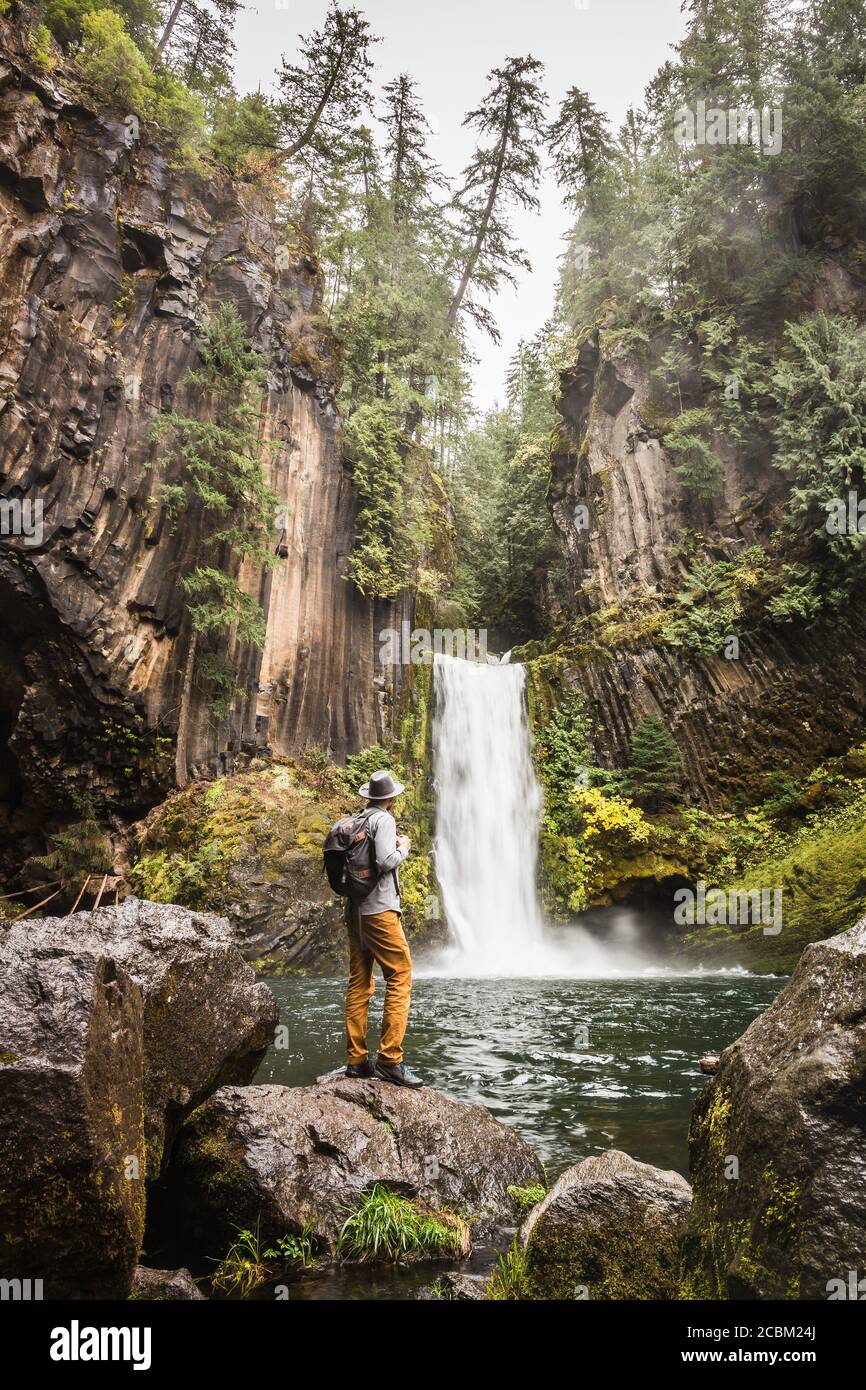 Man standing on boulder looking at Toketee Falls; Umpqua National Forest, Oregon, USA Stock Photo