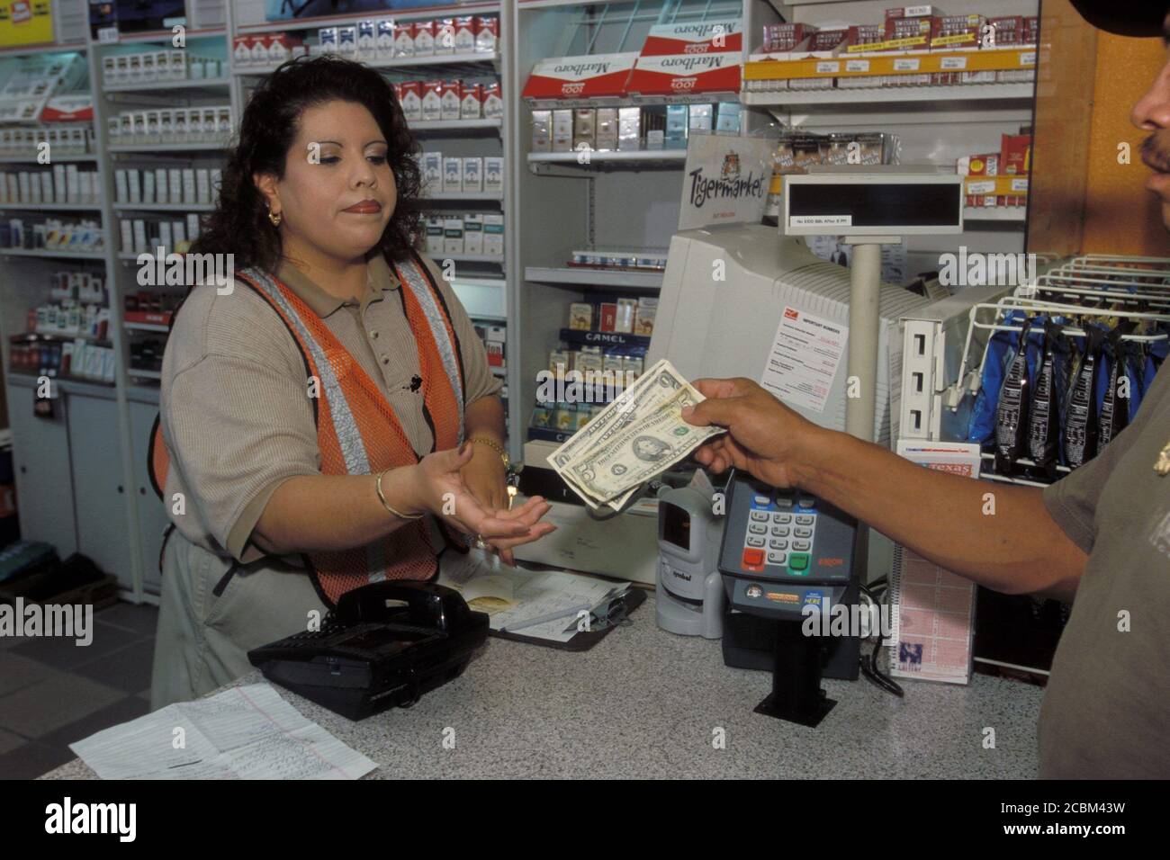 Austin, Texas USA, 2006: Female Hispanic clerk taking cash payment at an EXXON Mobil convenience store. ©Bob Daemmrich Stock Photo
