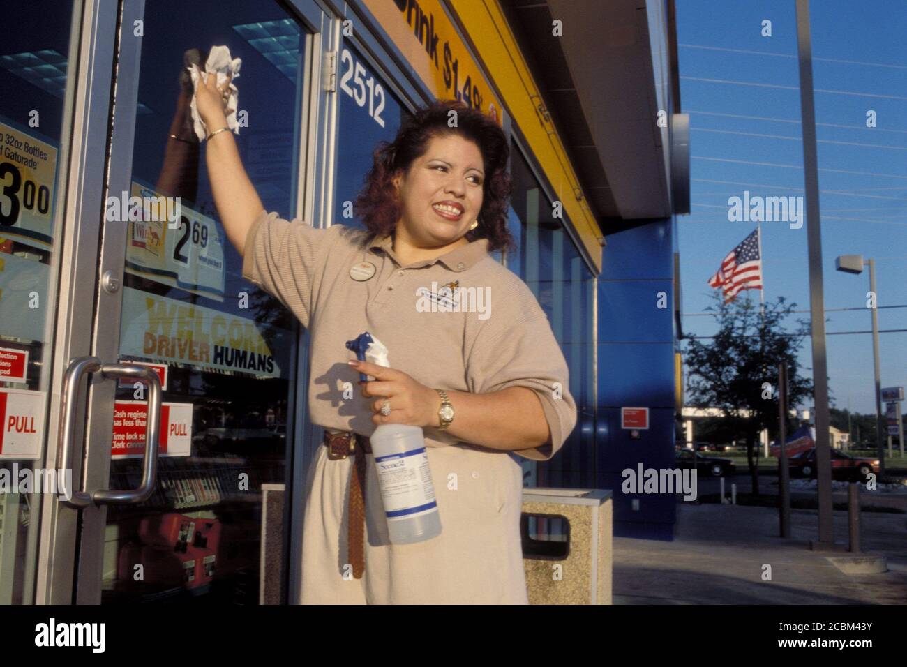 Austin, Texas USA, 2006: Hispanic woman washes windows at an EXXON Mobil convenience store where she is employed as a store clerk. ©Bob Daemmrich Stock Photo