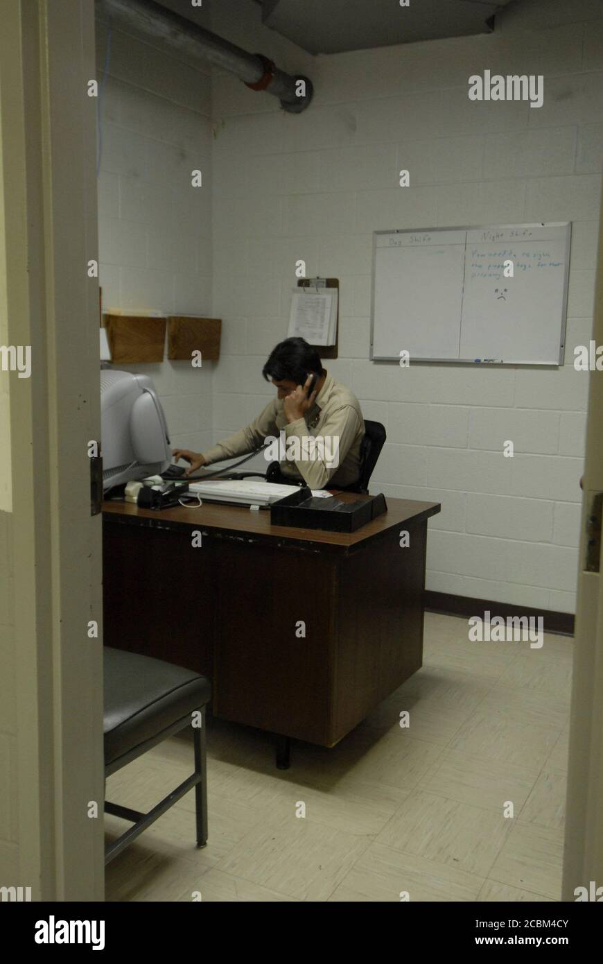 Del Rio, Texas: July, 2006. Hispanic sheriff's deputy talks on the phone with a citizen during a late night shift at the Val Verde County Sheriff's Office. ©Bob Daemmrich Stock Photo