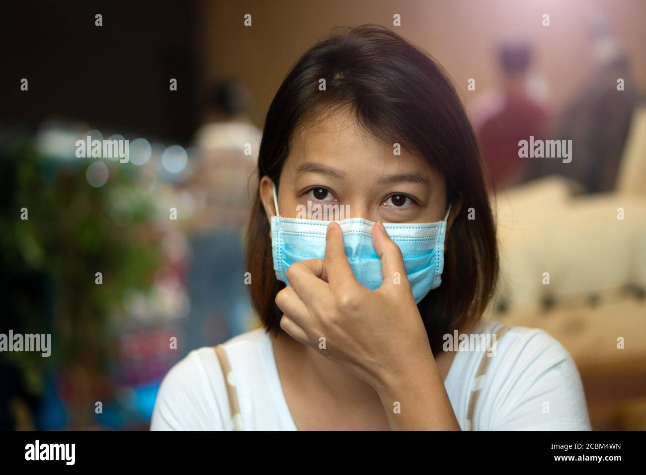 Asian woman wearing protective mask on her face while being in the coffee shop during virus COVID-19 pandemic. Stock Photo