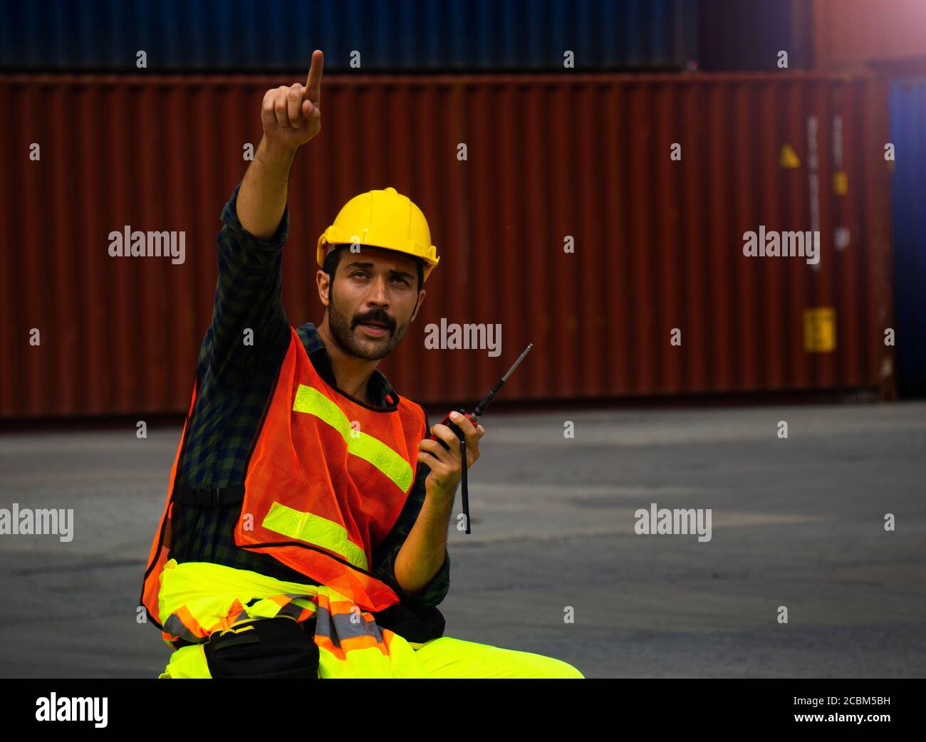 industrial worker is controlling container loading by walkie talkie in import-export business. Stock Photo