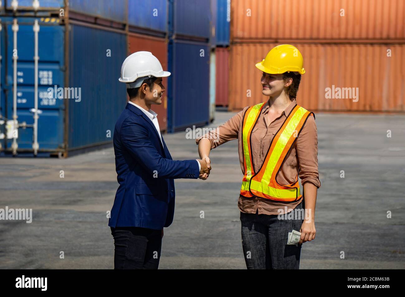 Business man and industrial worker woman shaking hands in background at container box Stock Photo