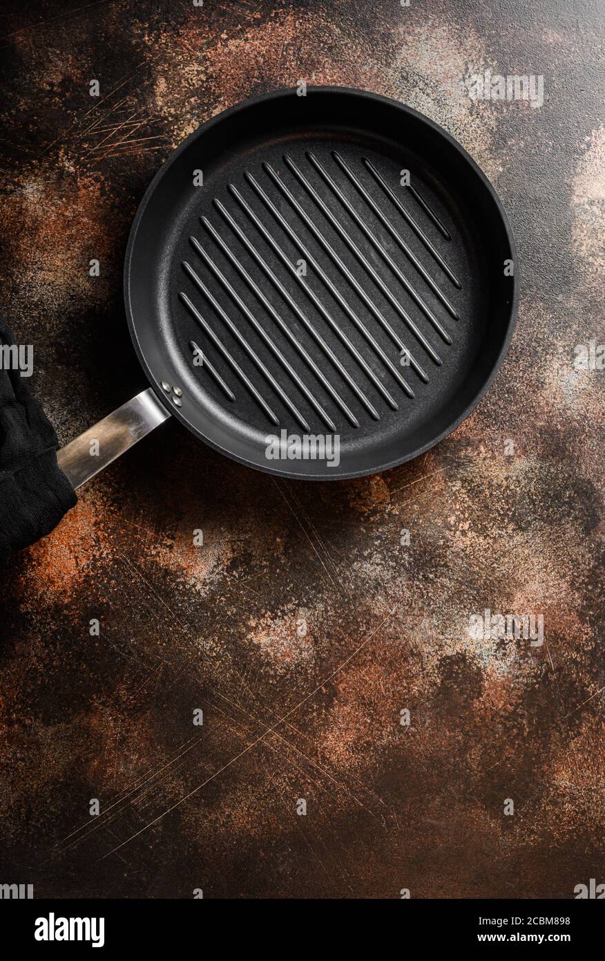 empty cast-iron grill pan skillet and linen cloth on metal rustic table top view space for text. Stock Photo