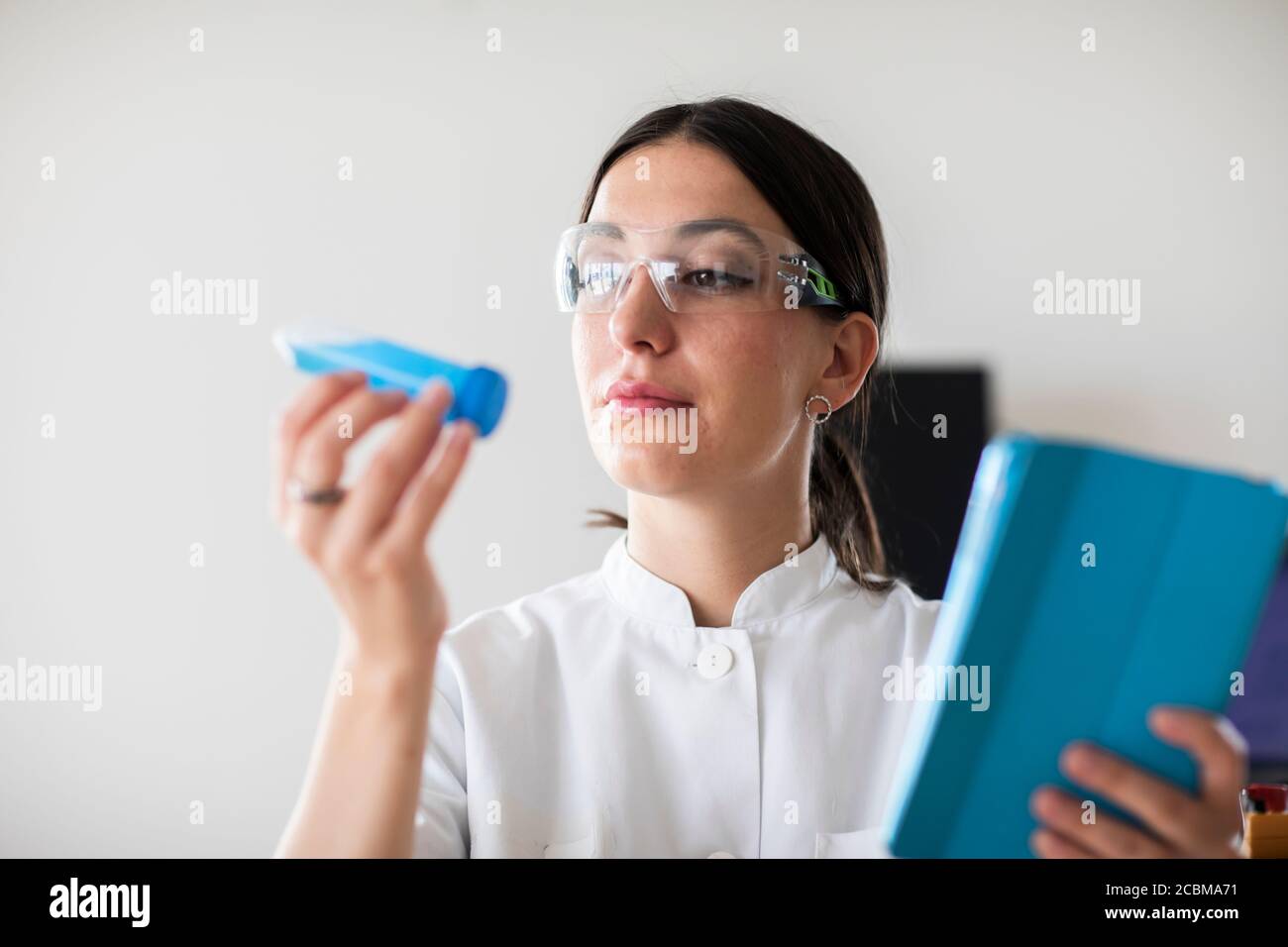 scientist female with lab glasses, tablet and tubes in a lab Stock