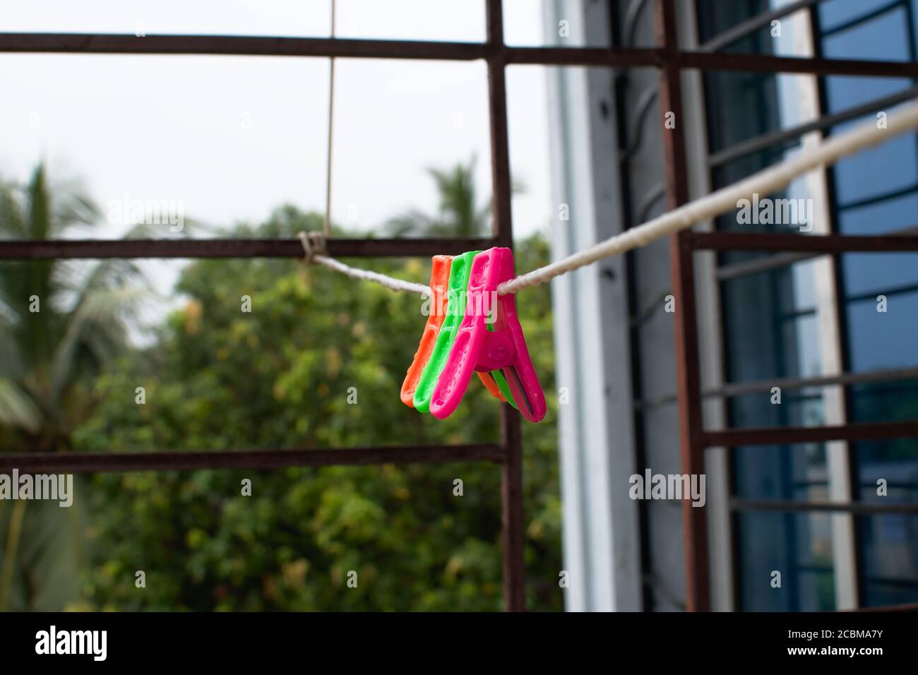 A trio of colorful plastic clothes pegs hanging on a washing line with blurred background Stock Photo