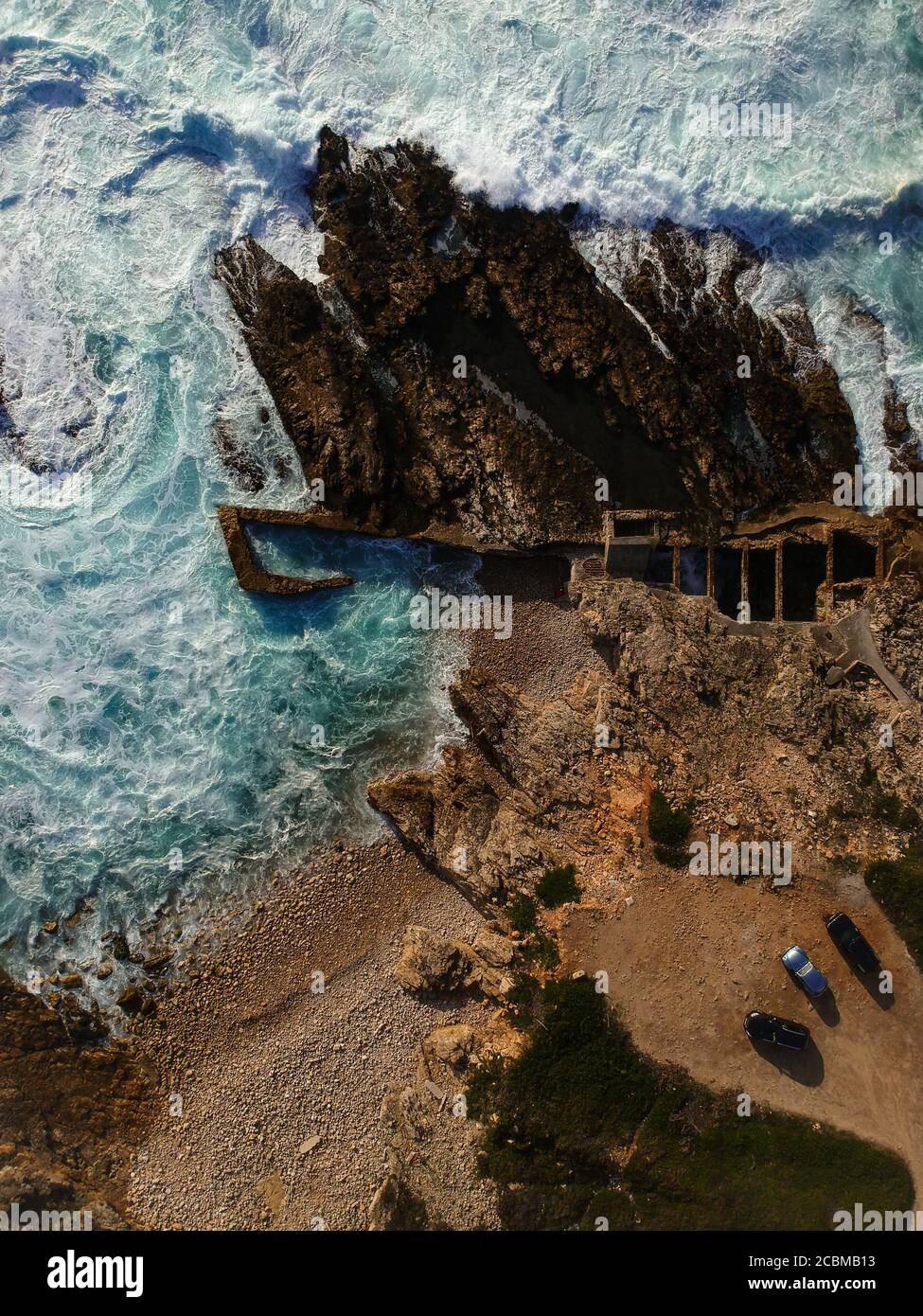 Aerial top view of sea waves hitting rocks on the beach with turquoise ...