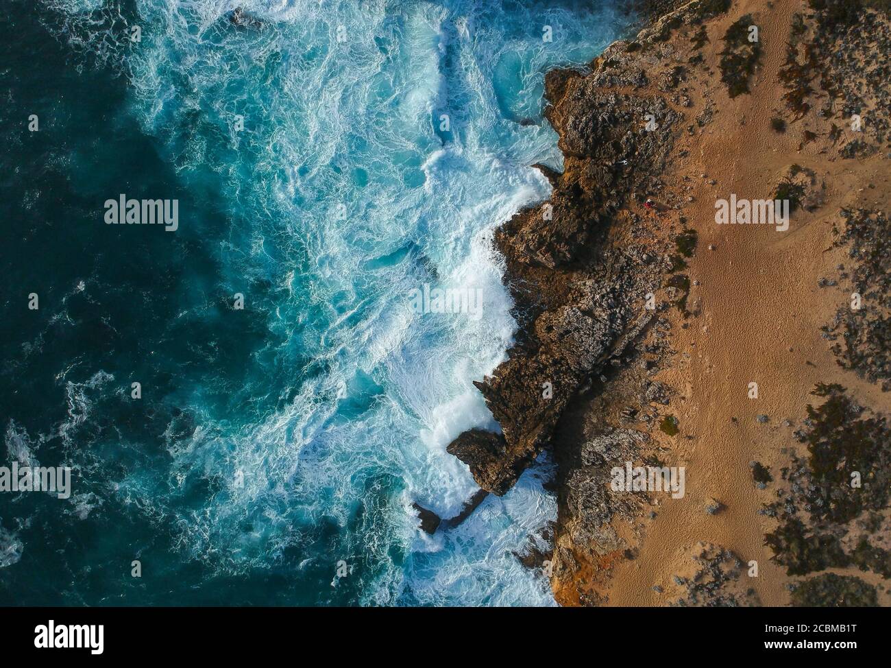 Aerial top view of sea waves hitting rocks on the beach with turquoise ...