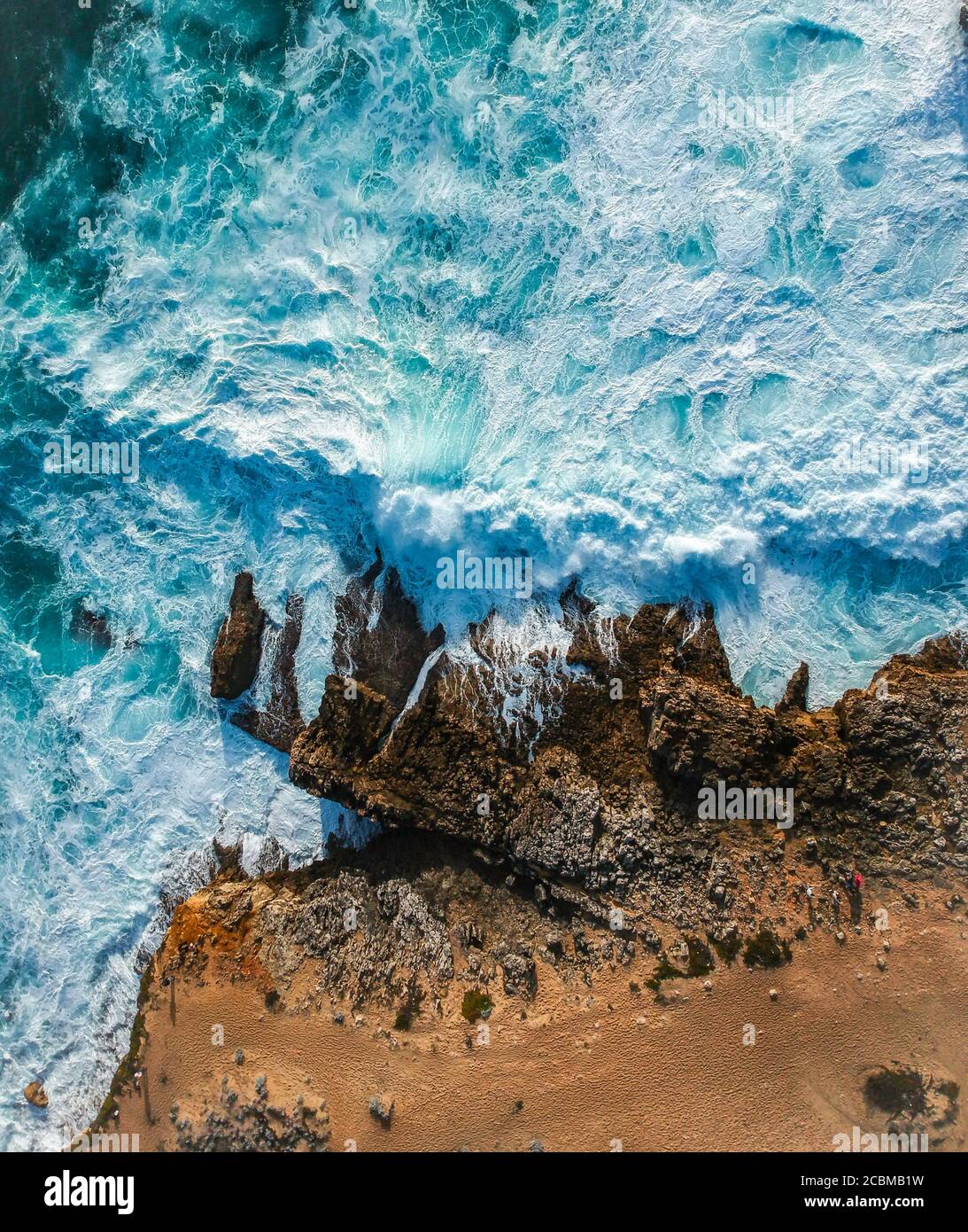 Aerial top view of sea waves hitting rocks on the beach with turquoise ...
