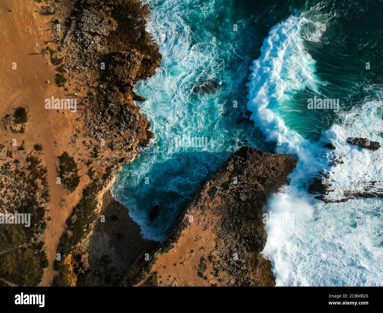Aerial top view of sea waves hitting rocks on the beach with turquoise ...
