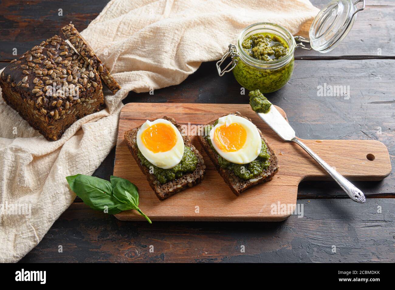 Fresh Green basil pesto in glass jar homemade on old rustic wood eggs panini bread with pesto