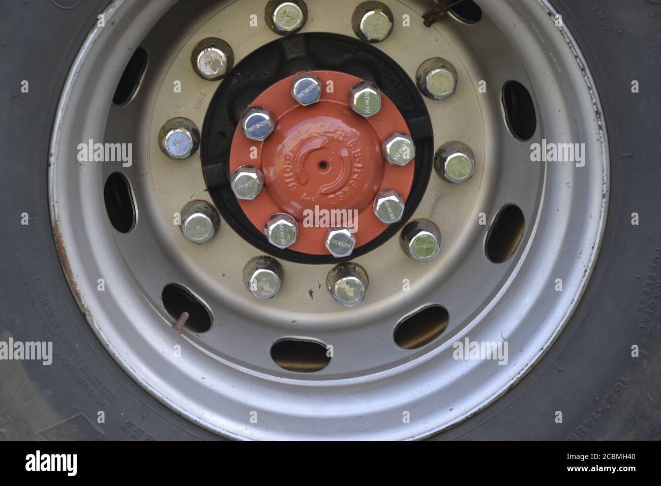 Truck wheel, in zoom photo, tire, rim, base rim, steel screws, bolt hole, disc and filling nozzle, in silver and blue Stock Photo