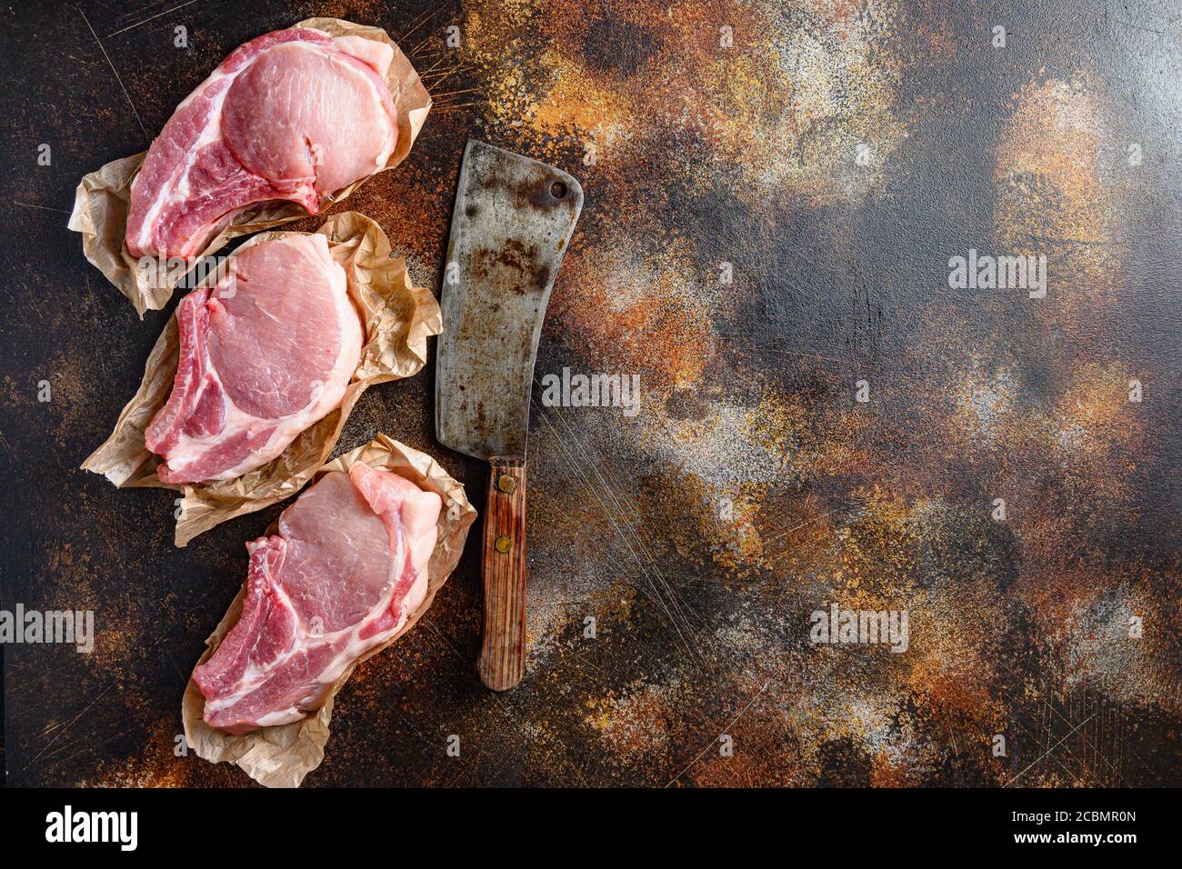 Bunch Pork steaks, fillets for grilling, baking or frying, Pork with ribs. Tenderloin. Entrecote warped in paper with butcher cleaver on side over Stock Photo