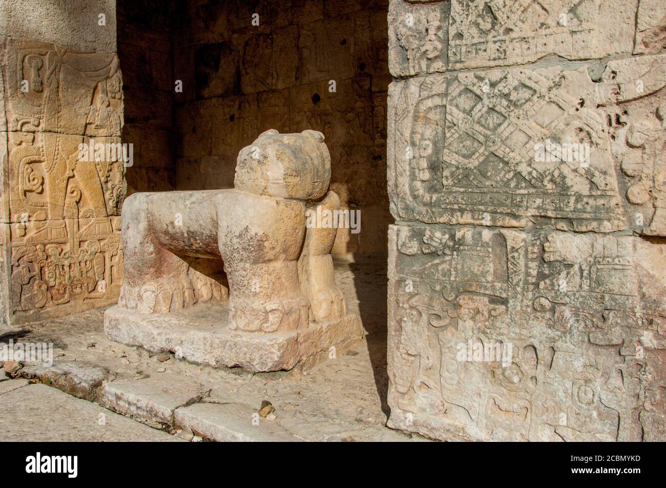 Ornate rock carvings and a statue on the outside wall of the ball court