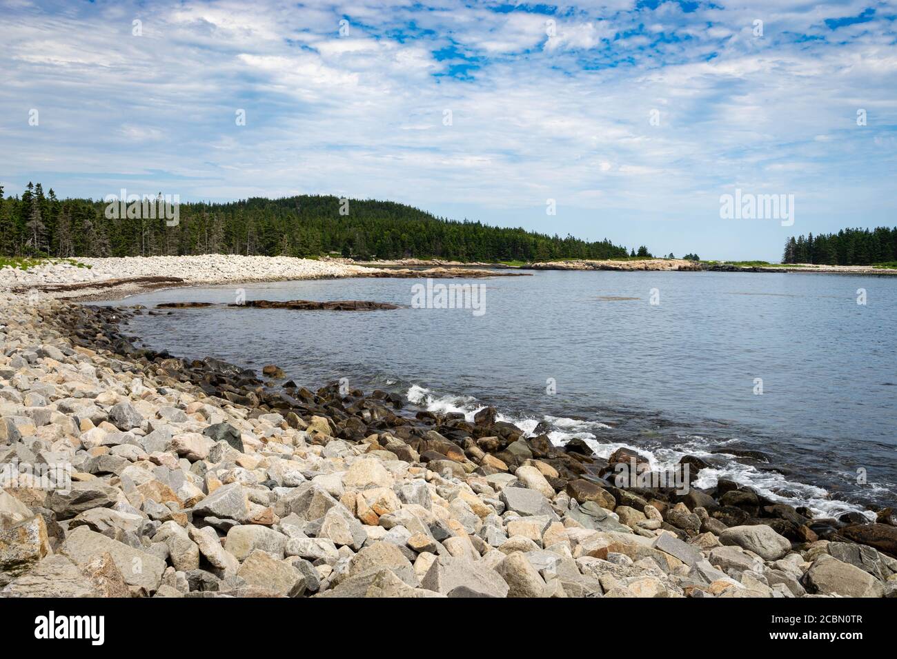 Trees sand rocks urround a cove in the Schoodic Peninsula in the Acadia National Park in Maine Stock Photo