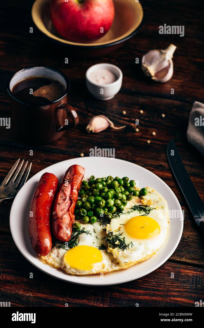 Breakfast with fried eggs, sausages and green peas Stock Photo Alamy