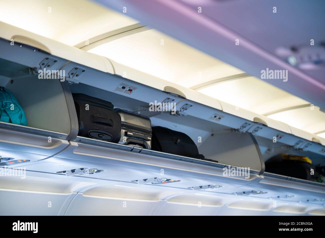Carryon luggage in overhead shelf in airplane cabin Stock Photo Alamy