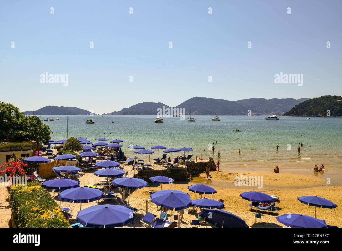 Scenic view of the Gulf of Poets from a sandy beach with sun umbrellas and people swimming and sunbathing in summer, Lerici, La Spezia, Liguria, Italy Stock Photo