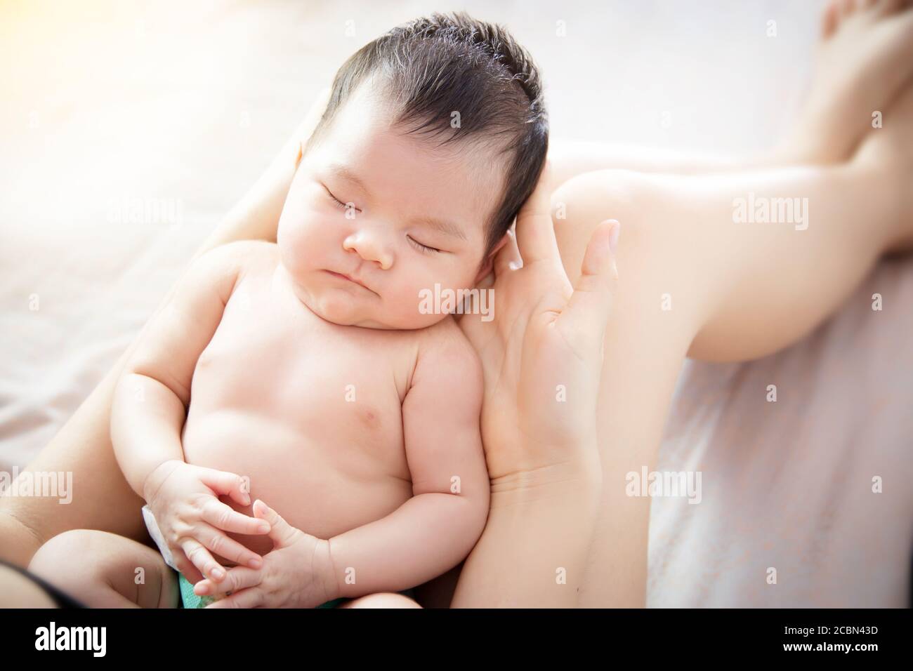 Concept of love and family relationship : close up newborn cute little Asian baby eye close feel comfortable to sleeping on hand of young mother at ho Stock Photo