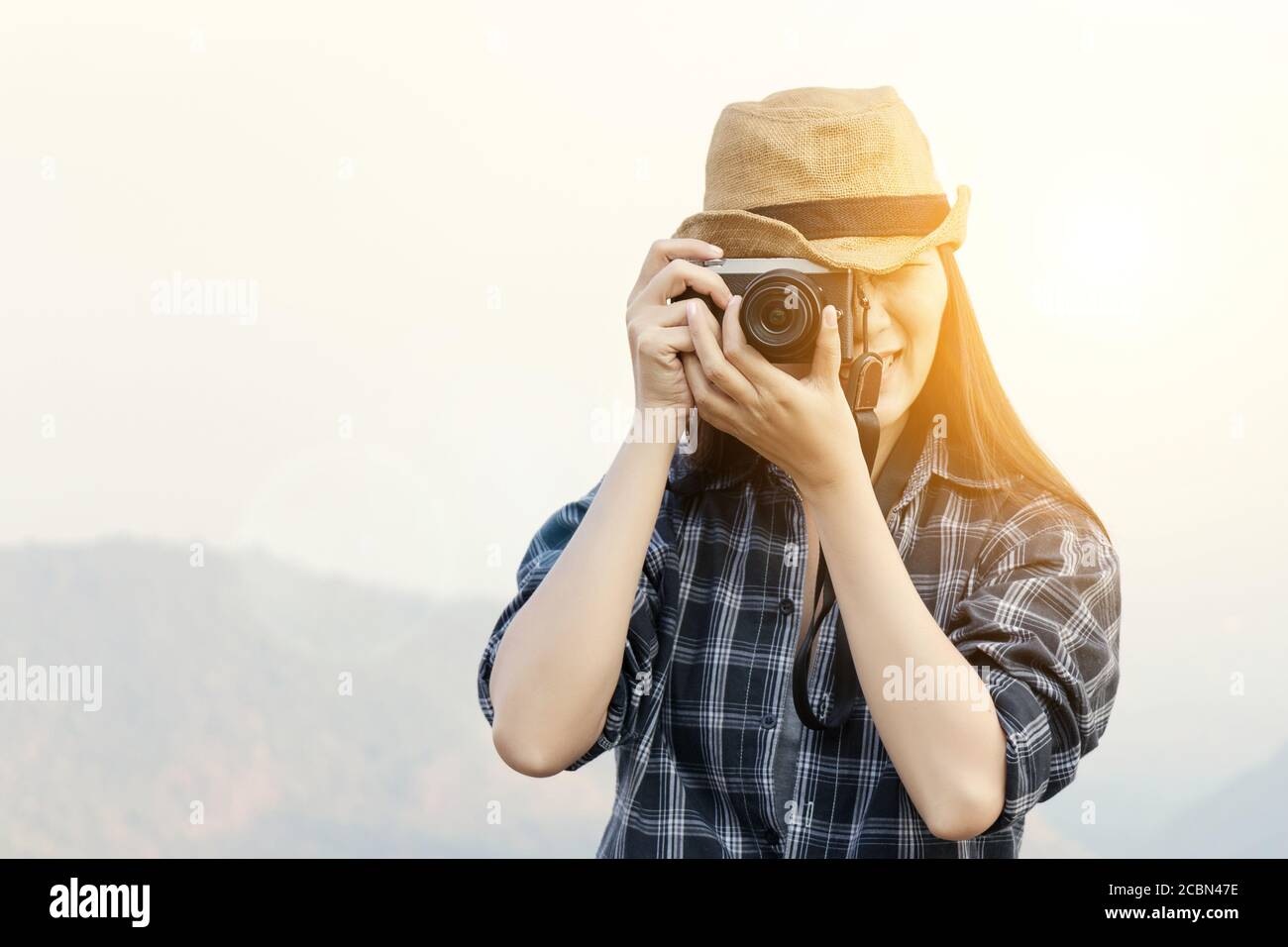 Travel Lifestyle vacations concept : Happy female traveler with camera making photo for good memory in tourist landmark at sunrise Stock Photo