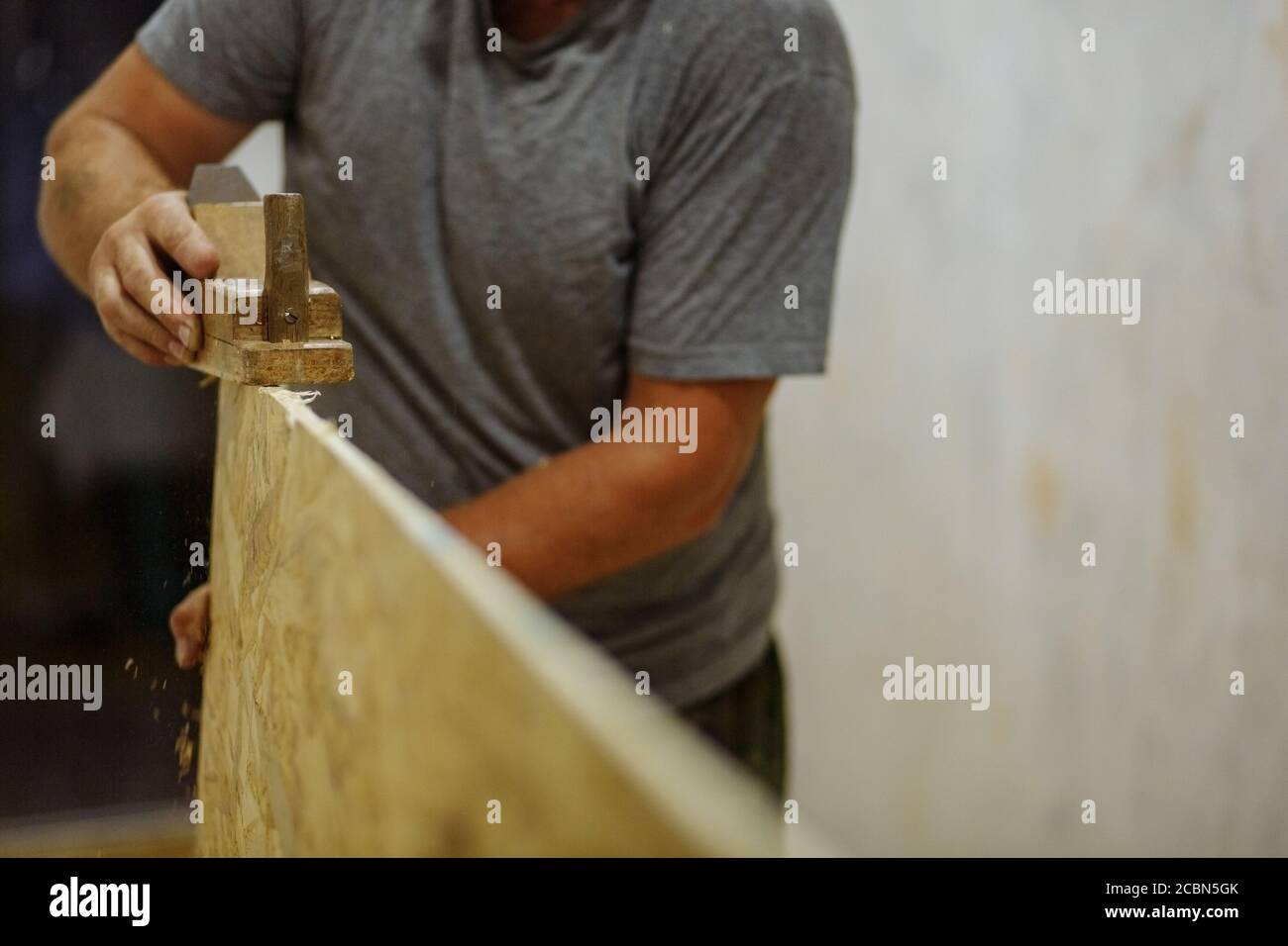 Man grinding the clapboard. Man working with wood. Home repair. Texture Stock Photo