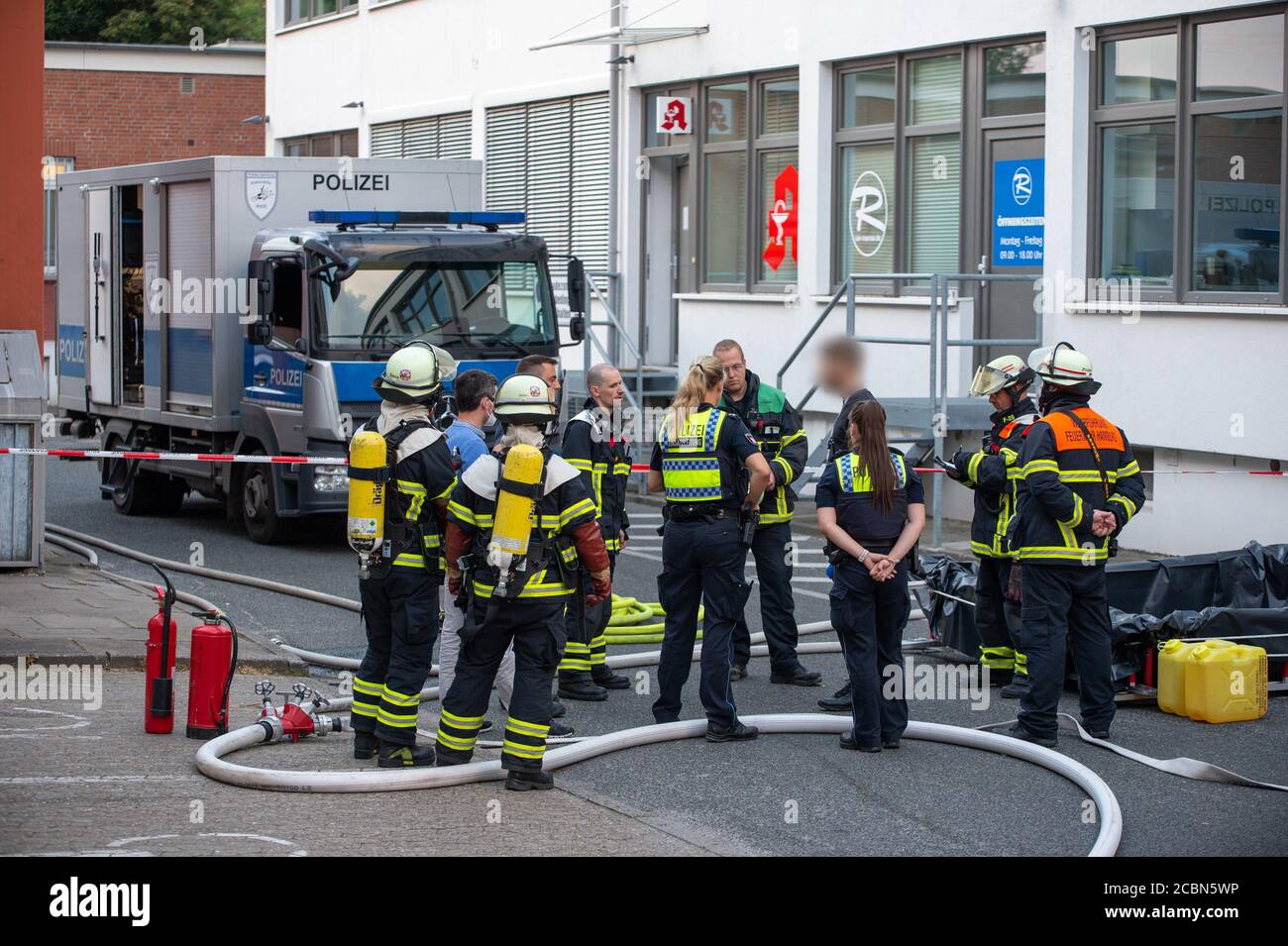 Hamburg, Germany. 14th Aug, 2020. Firefighters and police officers stand in front of a pharmacy. A pharmacist had discovered about 10 grams of dried, and therefore highly explosive, picric acid in the basement of the pharmacy in Horn on Friday evening. A shopping centre was partially evacuated. Credit: Jonas Walzberg/dpa - ATTENTION: A person was pixelated for legal reasons/dpa/Alamy Live News Stock Photo