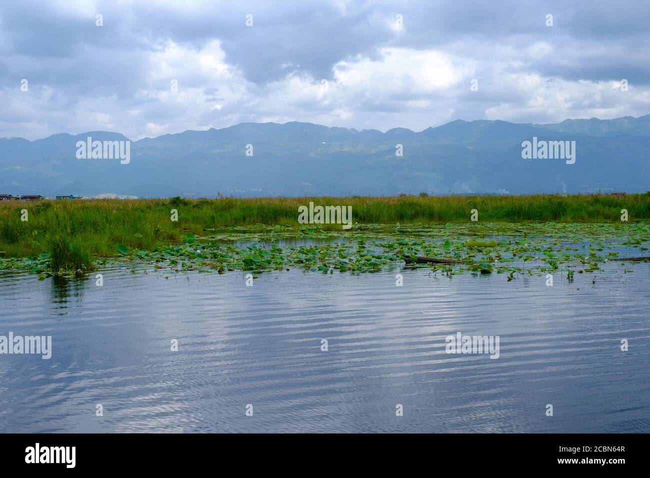 Taungthaman Lake, Amarapura U-Bein Bridge, Mandalay province, Myanmar. Sunset horizontal shot. Mountains reflecting in the water. Green nature. Stock Photo