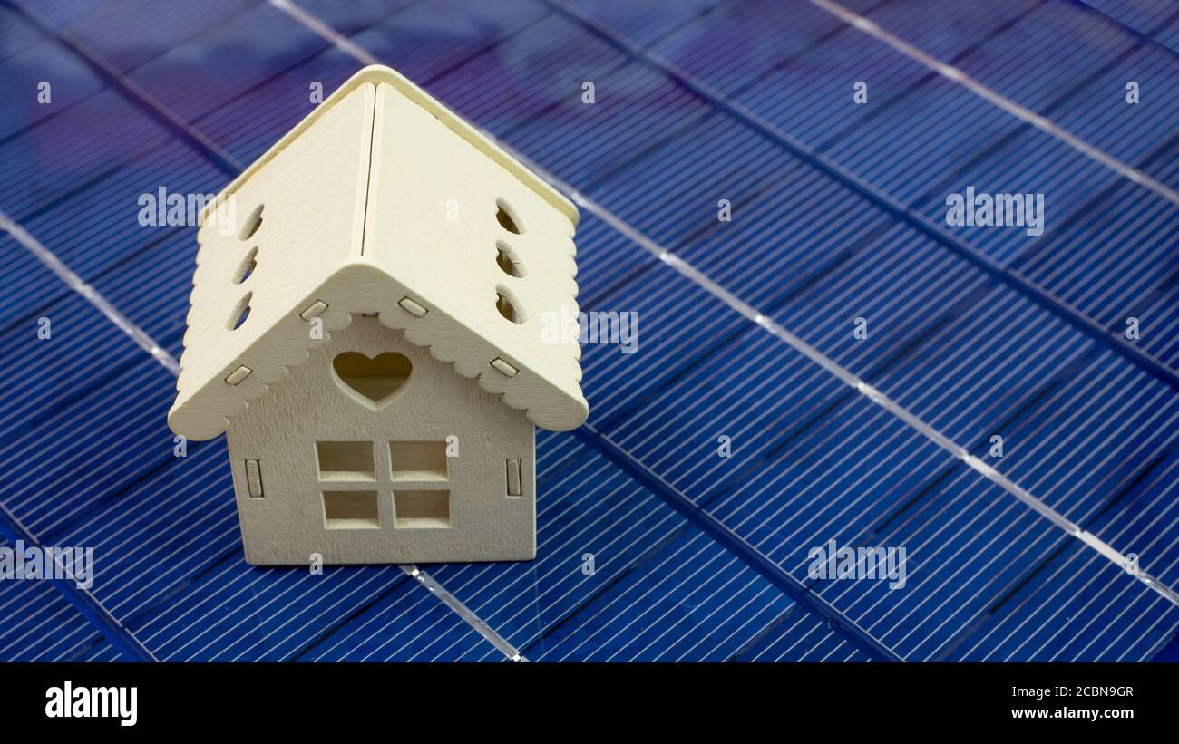 closeup of wooden house model on photovoltaic panel, concept of ecology and green energy, panorama Stock Photo