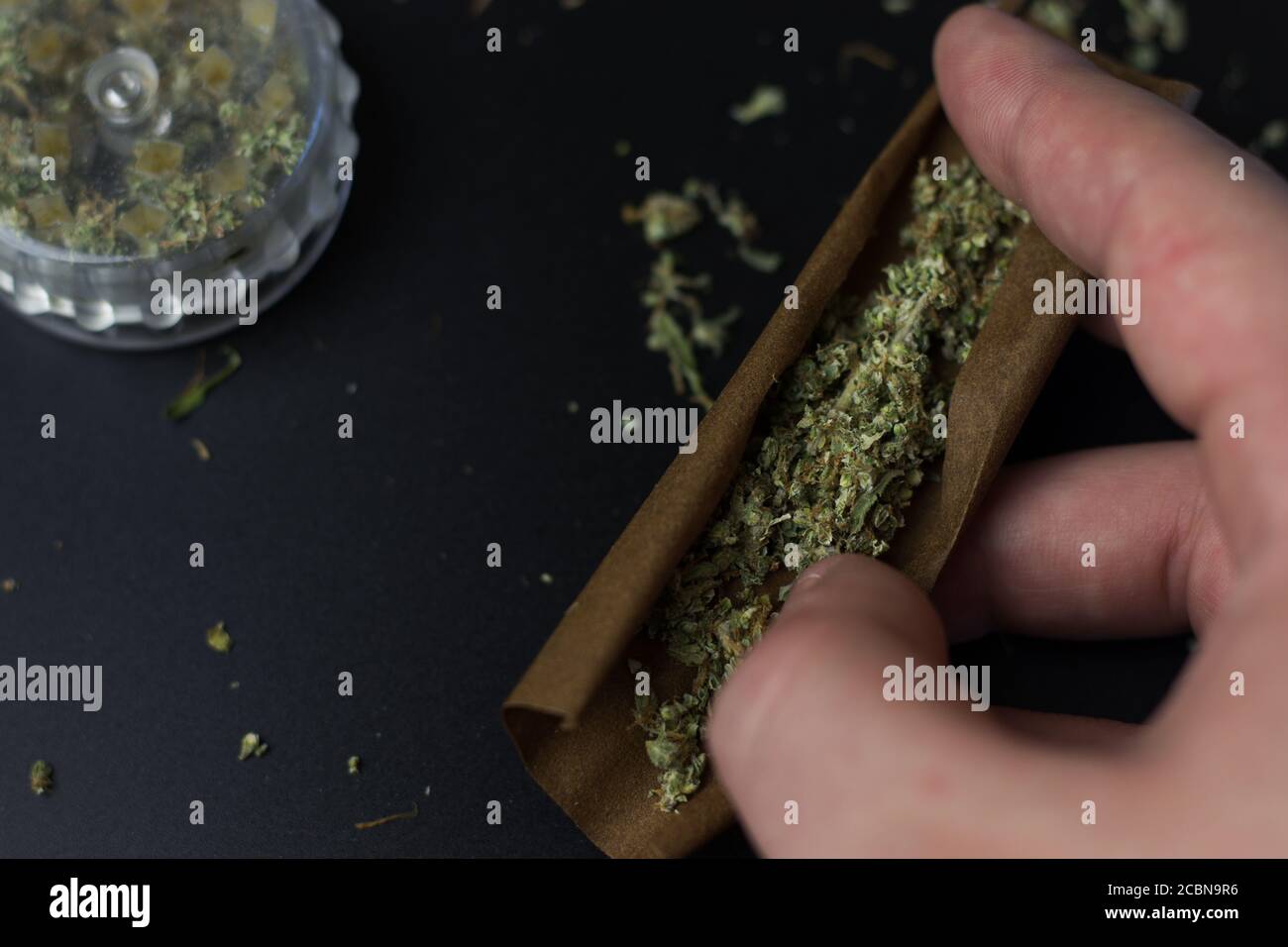 Hand holds cannabis in blunt roll paper. Marijuana medical and recreational use concept. Selfcare with herbal THC weed Stock Photo