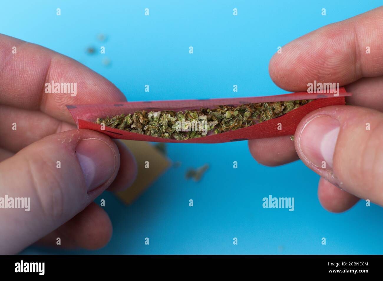 Man rolling joint with fruit tasted paper close-up top view Stock Photo -  Alamy