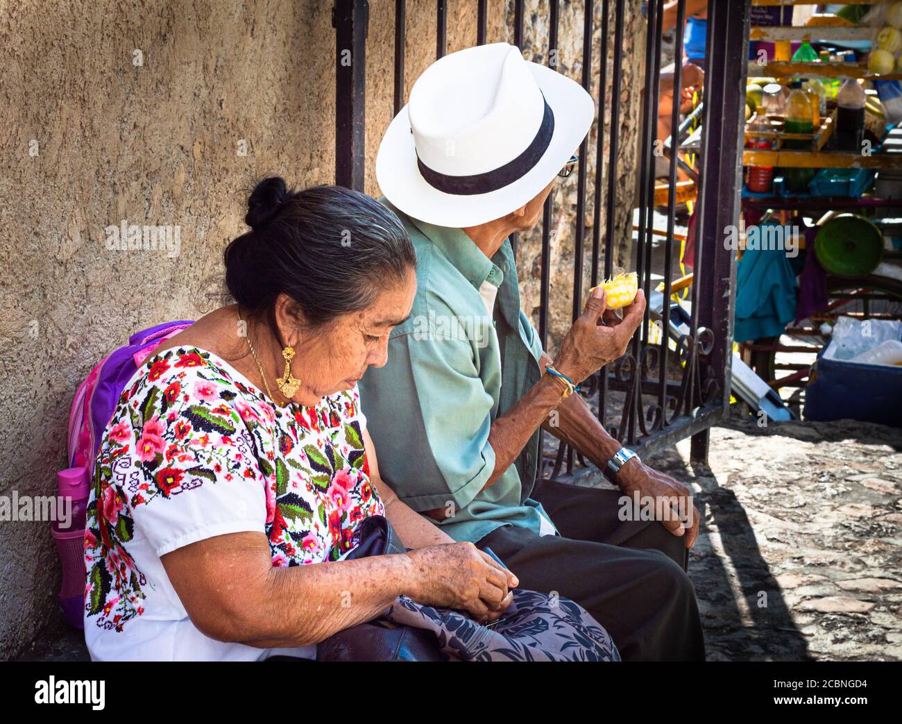 Mayan couple sitting in the shade during a hot day in Izamal, Yucatan, Mexico. Stock Photo