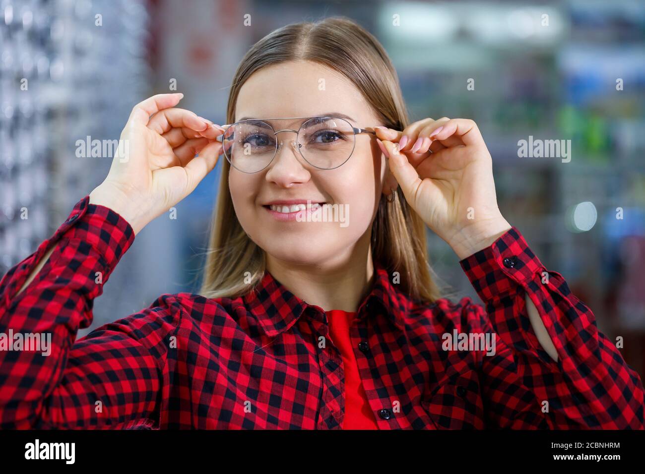 A visually impaired girl chooses glasses. She is wearing a shirt and a