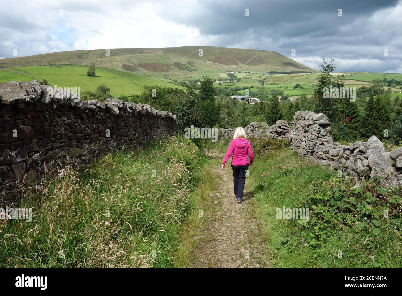Woman Walking to Pendle Hill on the Old Road to Barley from Roughlee in Pendle, Lancashire, England, UK. Stock Photo