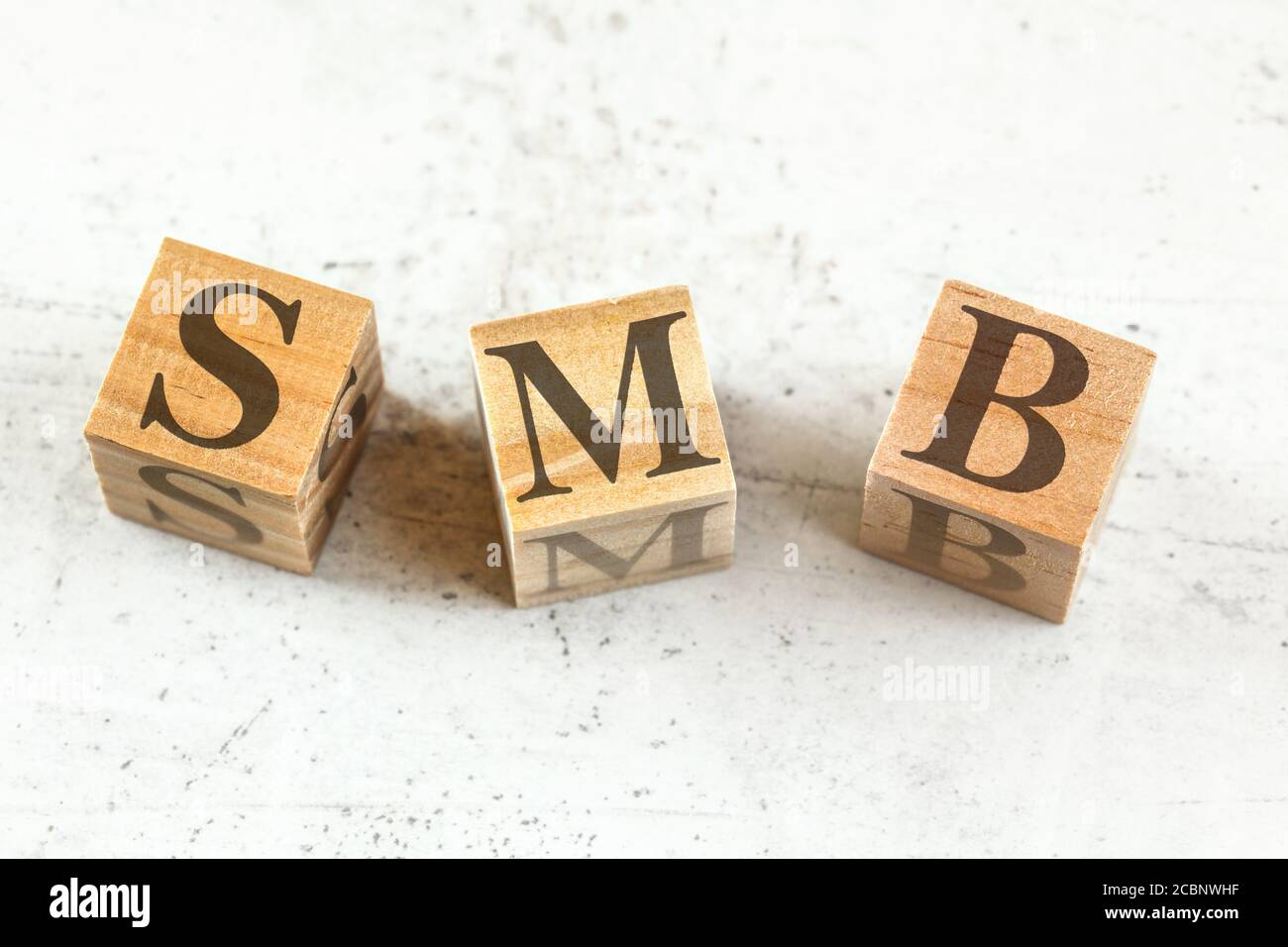 Three wooden cubes with letters SMB (stands for Small to medium Business) on white board. Stock Photo