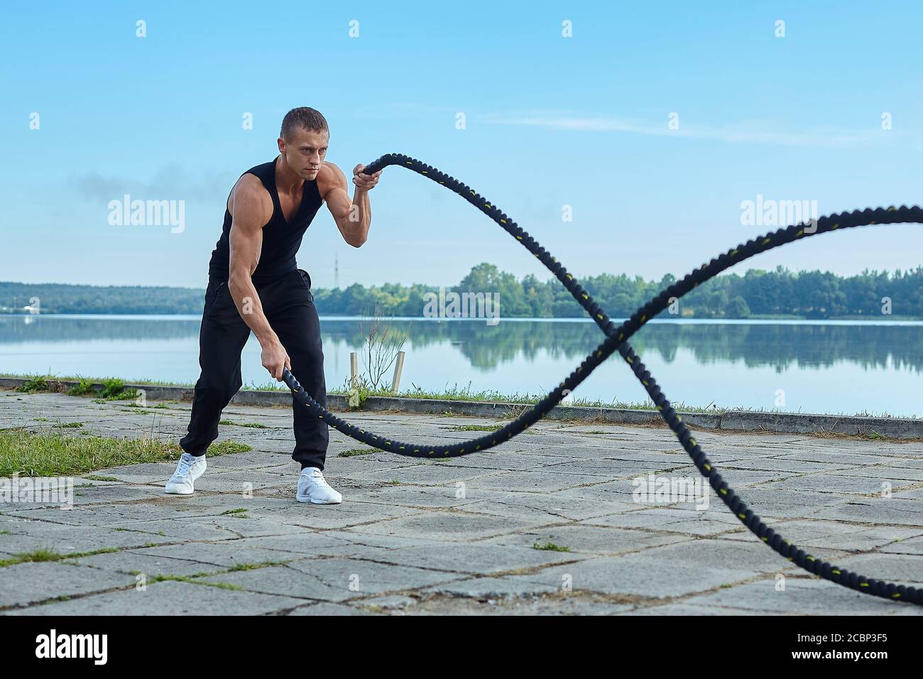 athletic man in the morning, against the background of the lake doing ...