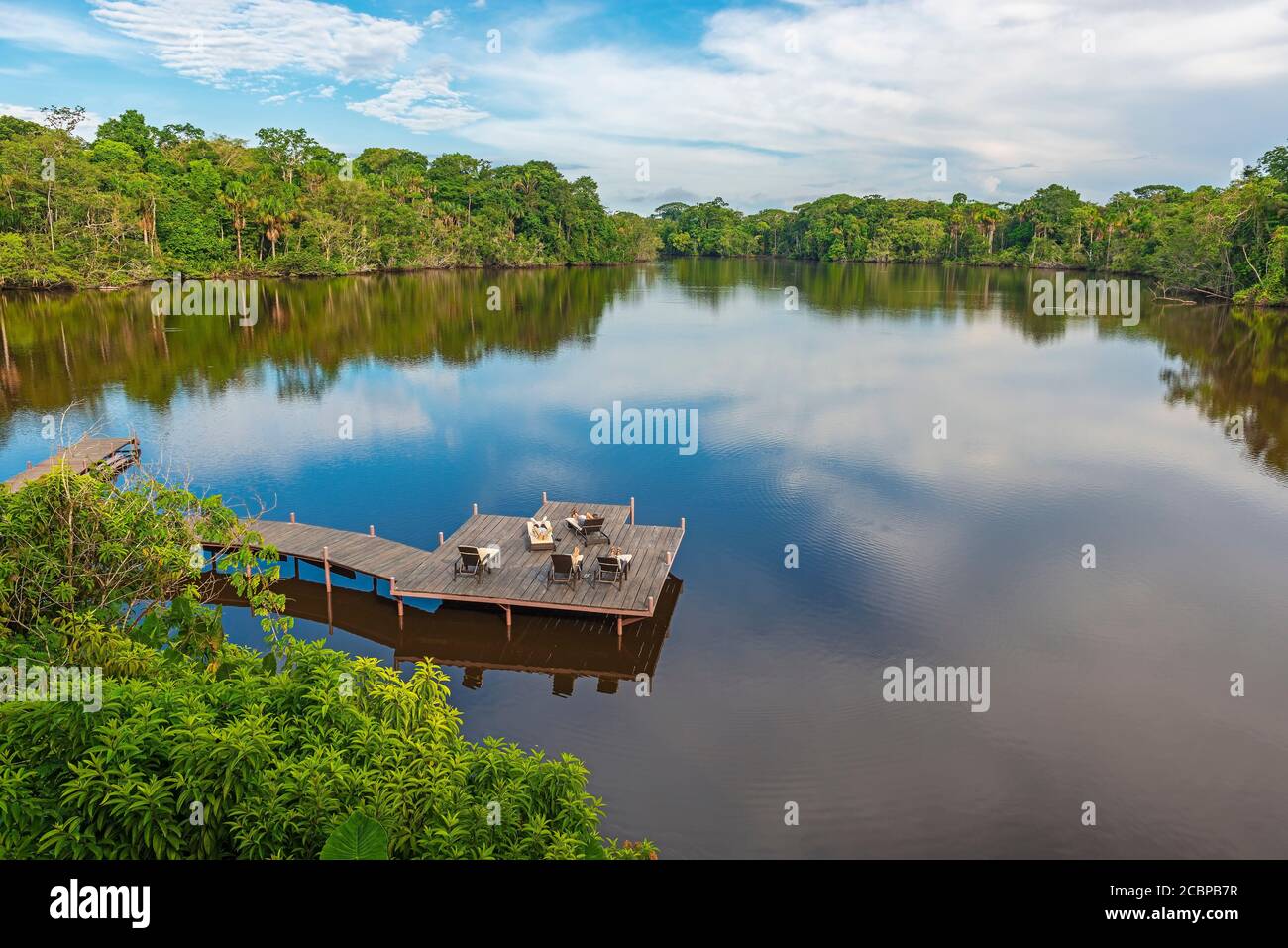 Tourists sunbathing on long chairs on a pier in an Amazon Rainforest lodge, Ecuador. Stock Photo