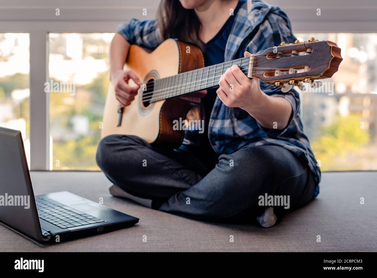 Woman learning online how to play guitar Stock Photo