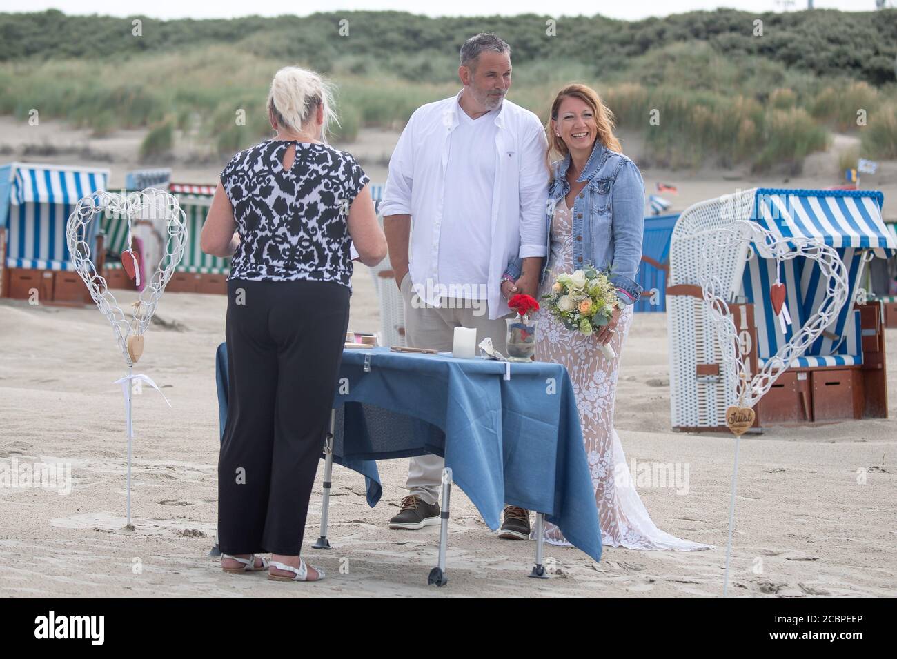 Juist, Germany. 14th Aug, 2020. Andreas and Annette Brand-Schimmelpfennig are married on the beach of Juist by registrar Katrin Wildenhein. Marriage with a view of the sea and their feet in the sand - numerous couples on the island of Juist take advantage of the rare opportunity to get married on the beach. (to dpa: 'Rare opportunity for a beach wedding: Already 100 weddings on Juist') Credit: Sina Schuldt/dpa/Alamy Live News Stock Photo