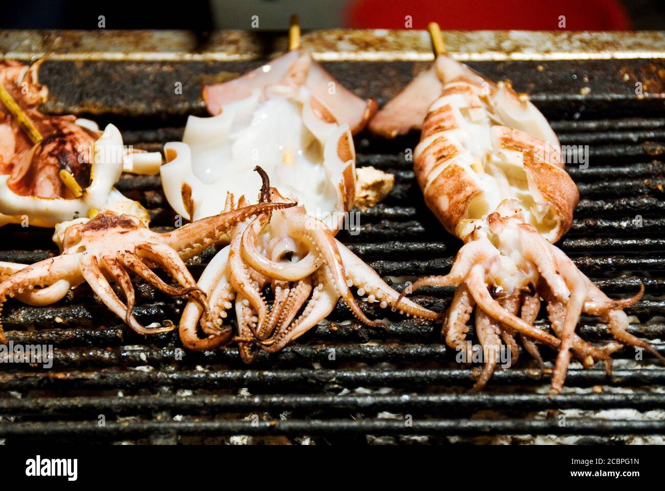 Stack of many grilled squid skewer on the grill in the night market