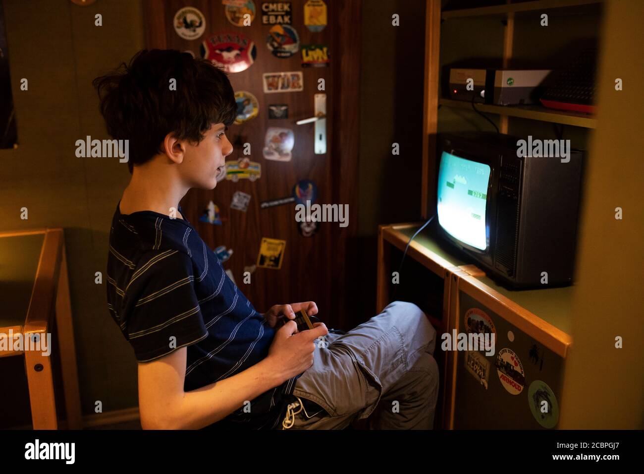 A fifteen-year-old teenage boy plays the original Mario Bros. Nintendo game at the Computerspiele Museum (video game museum) in Berlin, Germany. Stock Photo