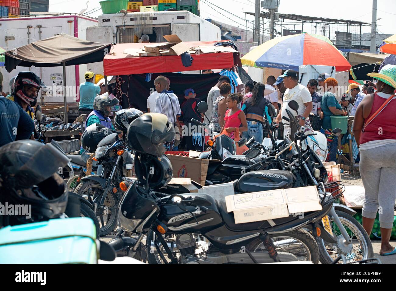 Cartagena Columbia outdoor market shoppers motorcycles. 5058. Historical poor neighborhood outdoor market. Raw fresh meat, beef, pork and fish prepared in hot unsanitary conditions. Dirty, smelly environment with rotten food. Local restaurants and shopping. Stock Photo