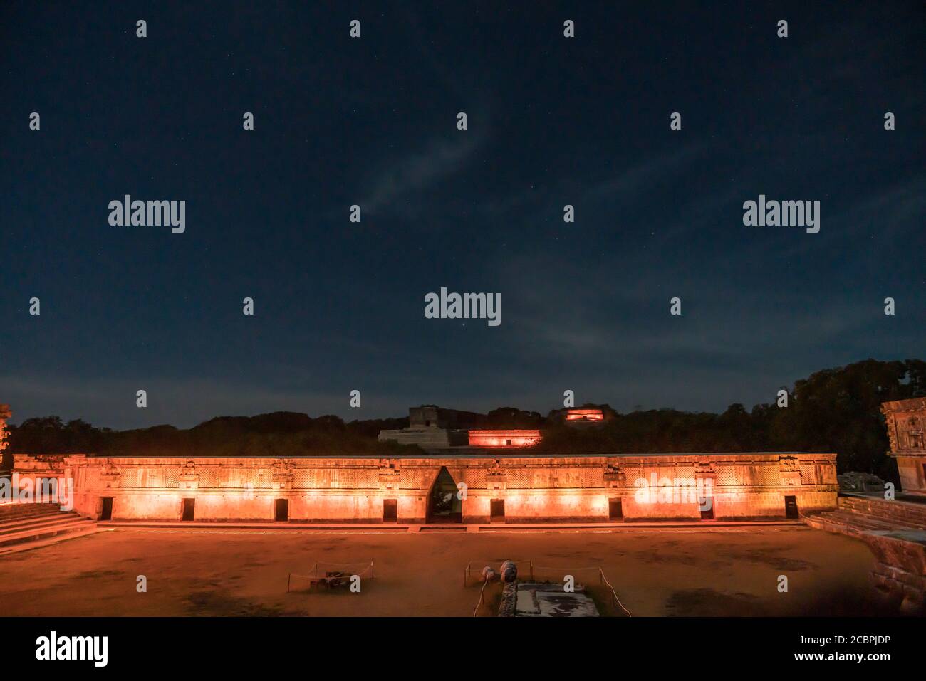 Lights on the south building of the Nunnery Quadrangle with the House of the Turtles and the Macaw Temple on the Great Pyramid behind in the pre-Hispa Stock Photo