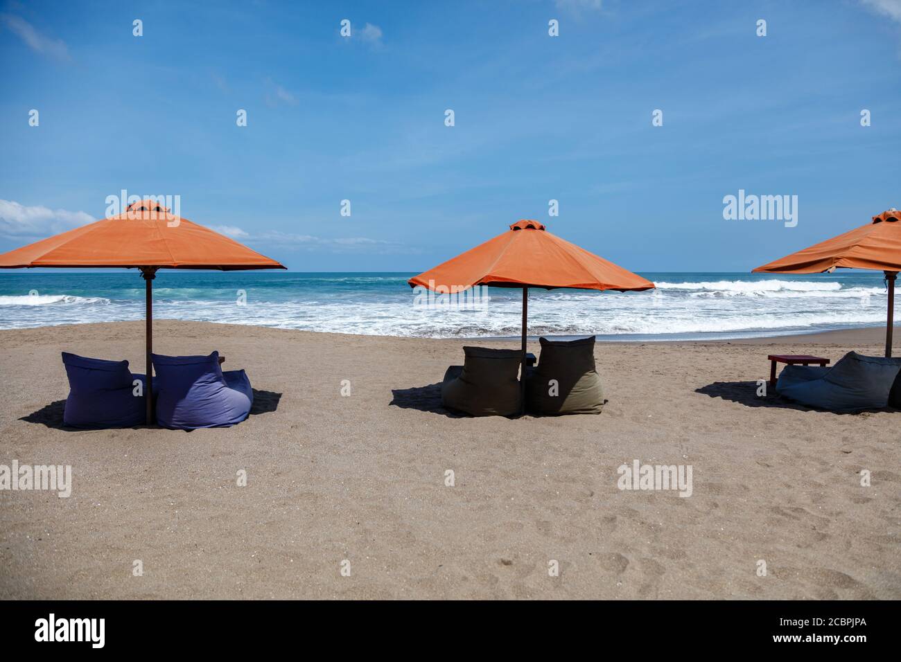 Orange sun umbrellas and empty bean bags on Berawa Beach (Pantai Berawa