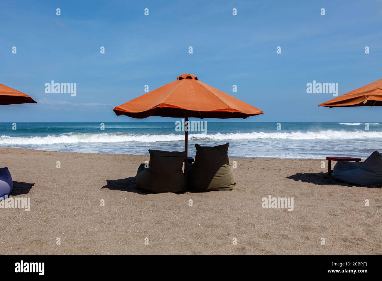 Orange sun umbrellas and empty bean bags on Berawa Beach (Pantai Berawa
