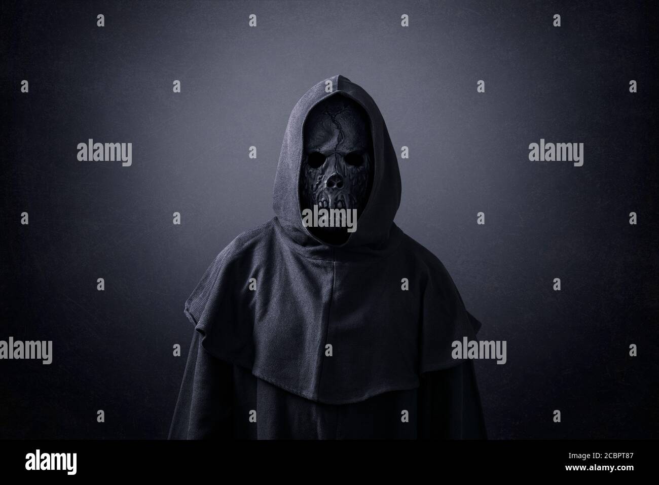 Scary figure in hooded cloak in the dark Stock Photo