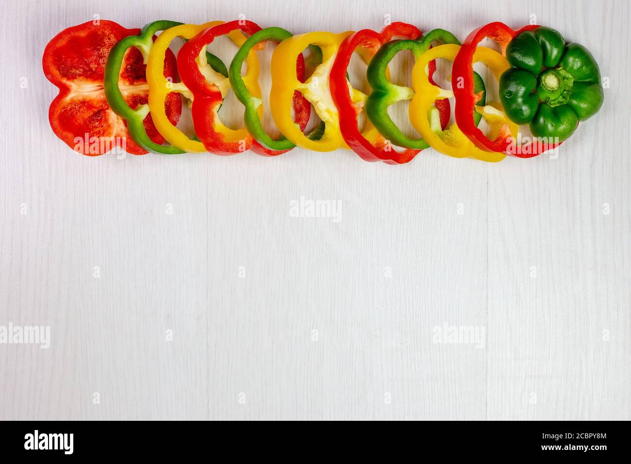 fresh peppers sliced red green yellow, white background Stock Photo - Alamy