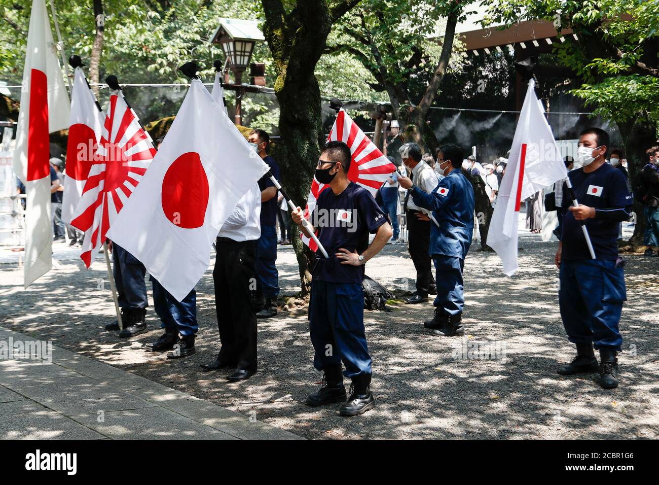 Tokyo, Japan. 15th Aug, 2020. Japanese nationalists wearing face masks hold war flags of the Imperial Japanese Army during the 75th anniversary of Japan's surrender in World War II at Yasukuni Shrine. This year, the temple has set signboards promoting the social distancing to prevent the spreading of the new coronavirus (COVID-19) disease at the Yasukuni Shrine. Credit: Rodrigo Reyes Marin/ZUMA Wire/Alamy Live News Stock Photo